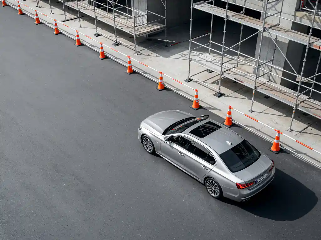 Zilveren zakenauto geparkeerd naast moderne bouwplaats met oranje verkeerskegels en steiger