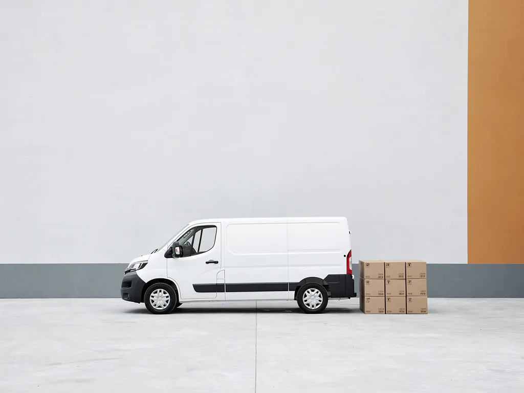 Witte bezorgbus geparkeerd op beton naast een nette rij gestapelde kartonnen dozen, minimalistisch en zakelijk.