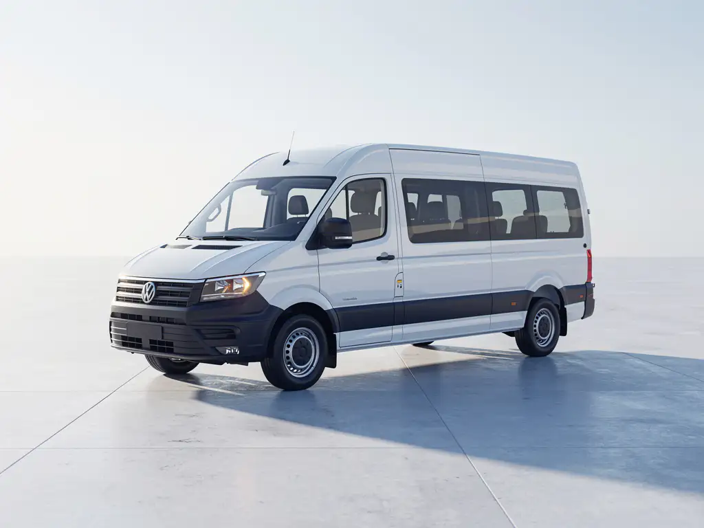 Witte 9-persoons minibus geparkeerd op beton, gefotografeerd vanuit laag driekwart perspectief in zacht ochtendlicht.